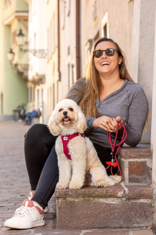 Frau sitzt mit weißem Hund auf Steintreppe