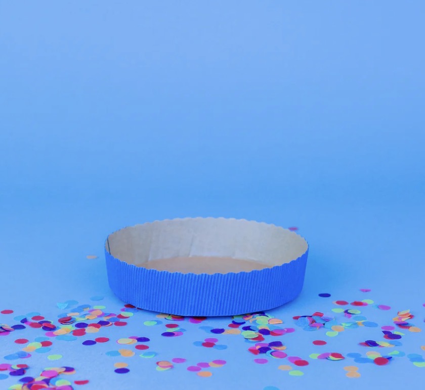 Eine blaue Kuchenbackform in einem blauen Hintergrund mit Konfetti 