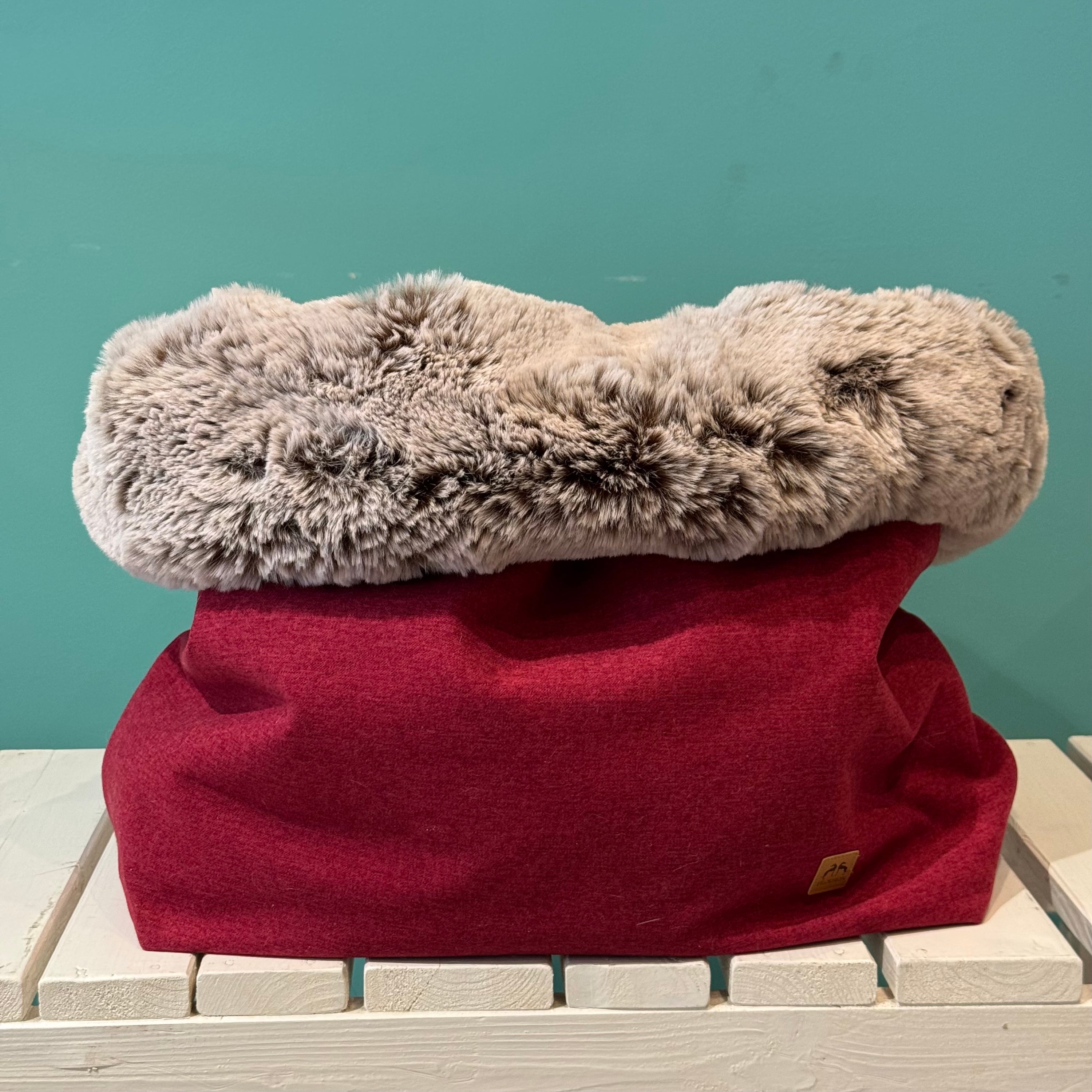 Kuschelsack in Rot auf einer weißen Bank 