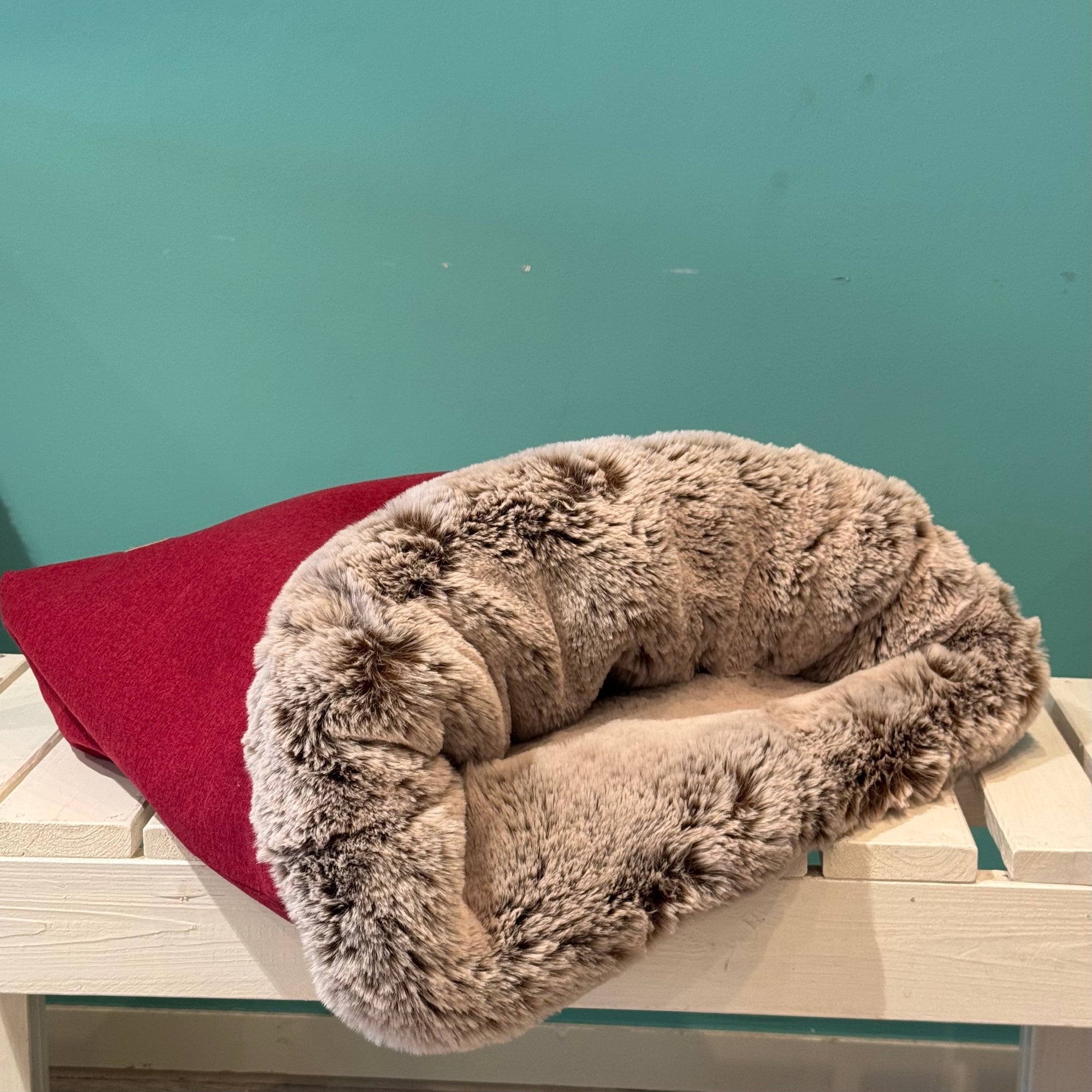 Liegender Kuschelsack in Rot auf einer weißen Bank 