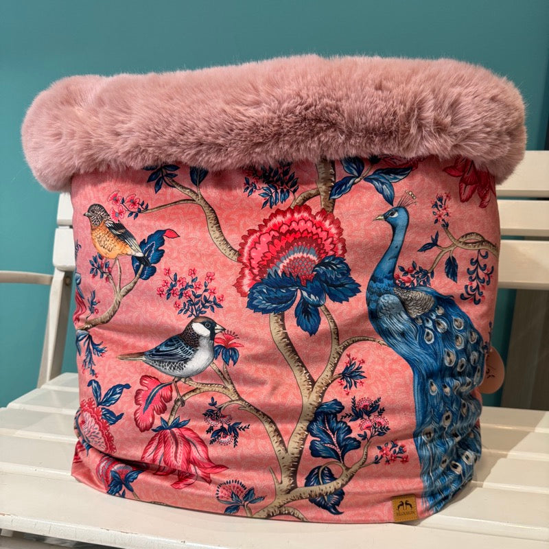 Kuschelhöhle für Hunde auf einer Bank stehend. Pfau und Meisenmuster auf rosa Grund