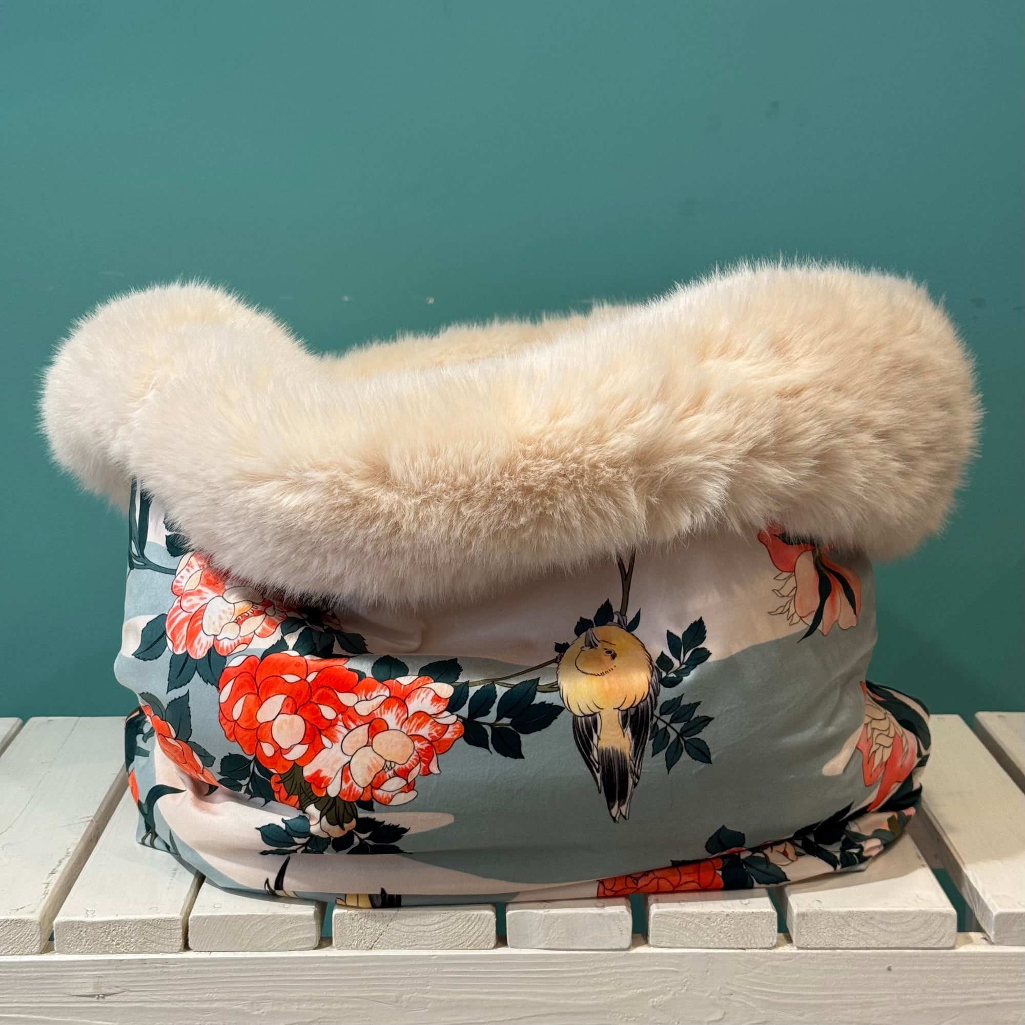 Kuschelsack mit Vogelmotiv in blau weiß auf einer weißen Bank 