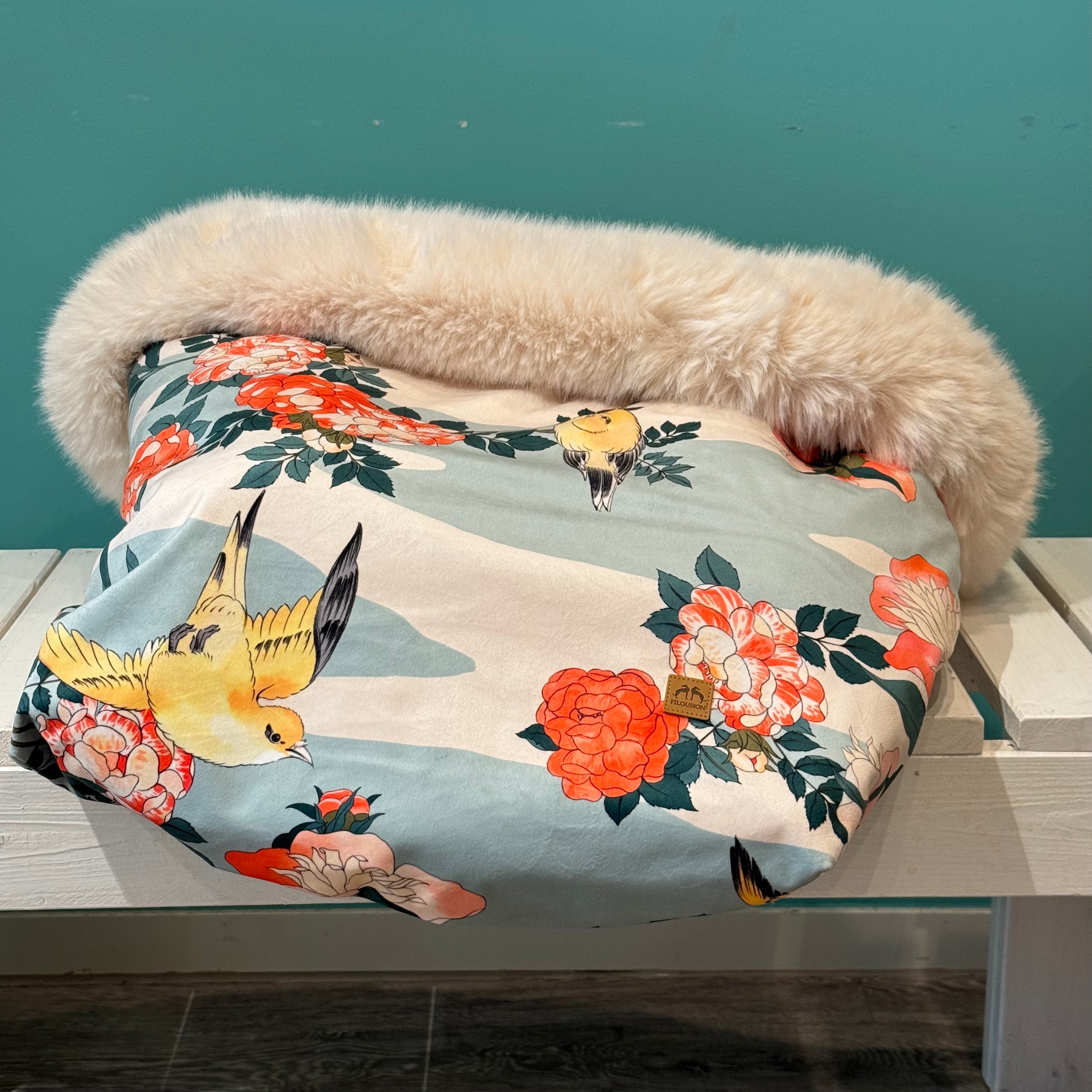 Kuschelsack mit Vogelmotiv in blau weiß auf einer weißen Bank Liegend 