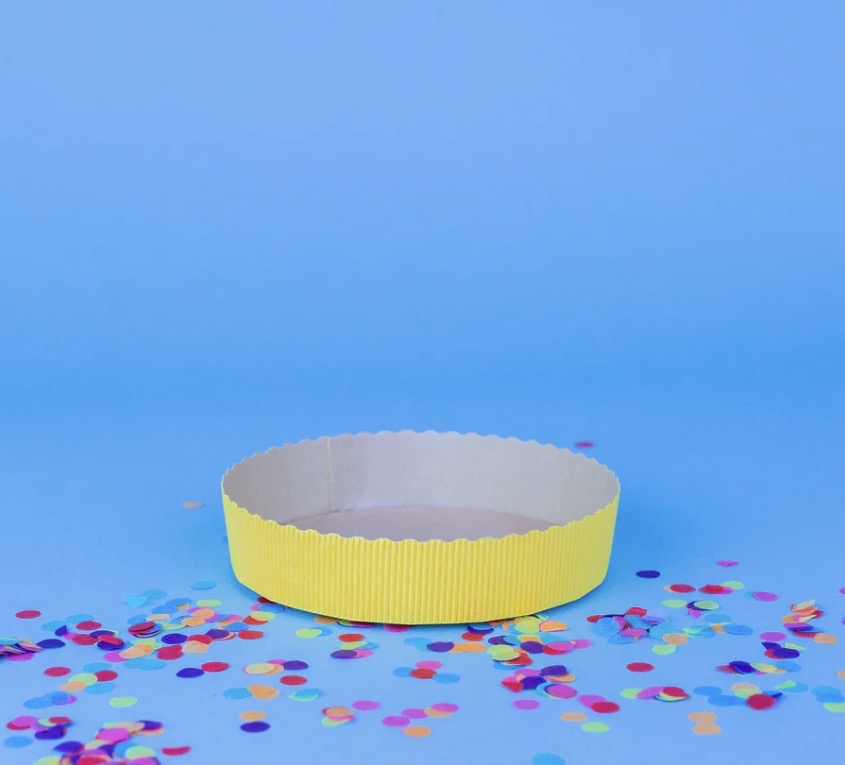 Eine gelbe Kuchenbackform auf einem blauen Hintergrund mit Konfetti