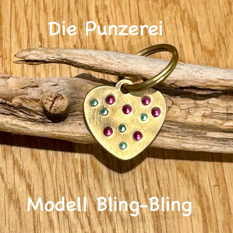 Handgepunzte Hundemarke aus Messing , herzförmiges Design mit bunten Steinchen an Schlüsselring befestigt, präsentiert auf Holzuntergrund