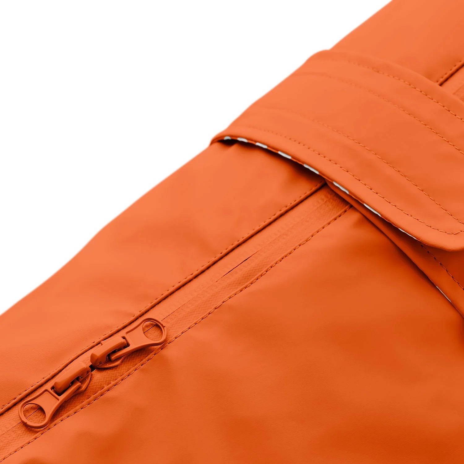 Detailaufnahme des orangen Hunderegenmantels mit Reißverschluss und Klettverschluss.