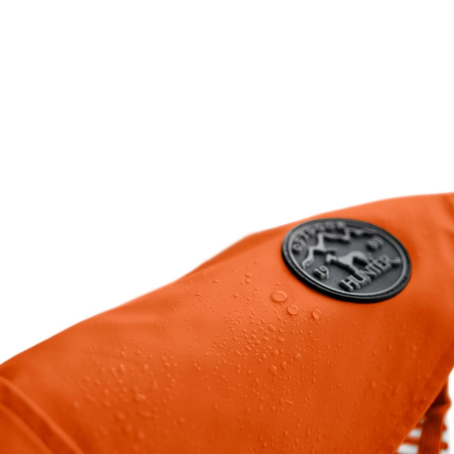 Nahaufnahme des wasserabweisenden Materials des orangen Hunderegenmantels mit Logo-Patch.
