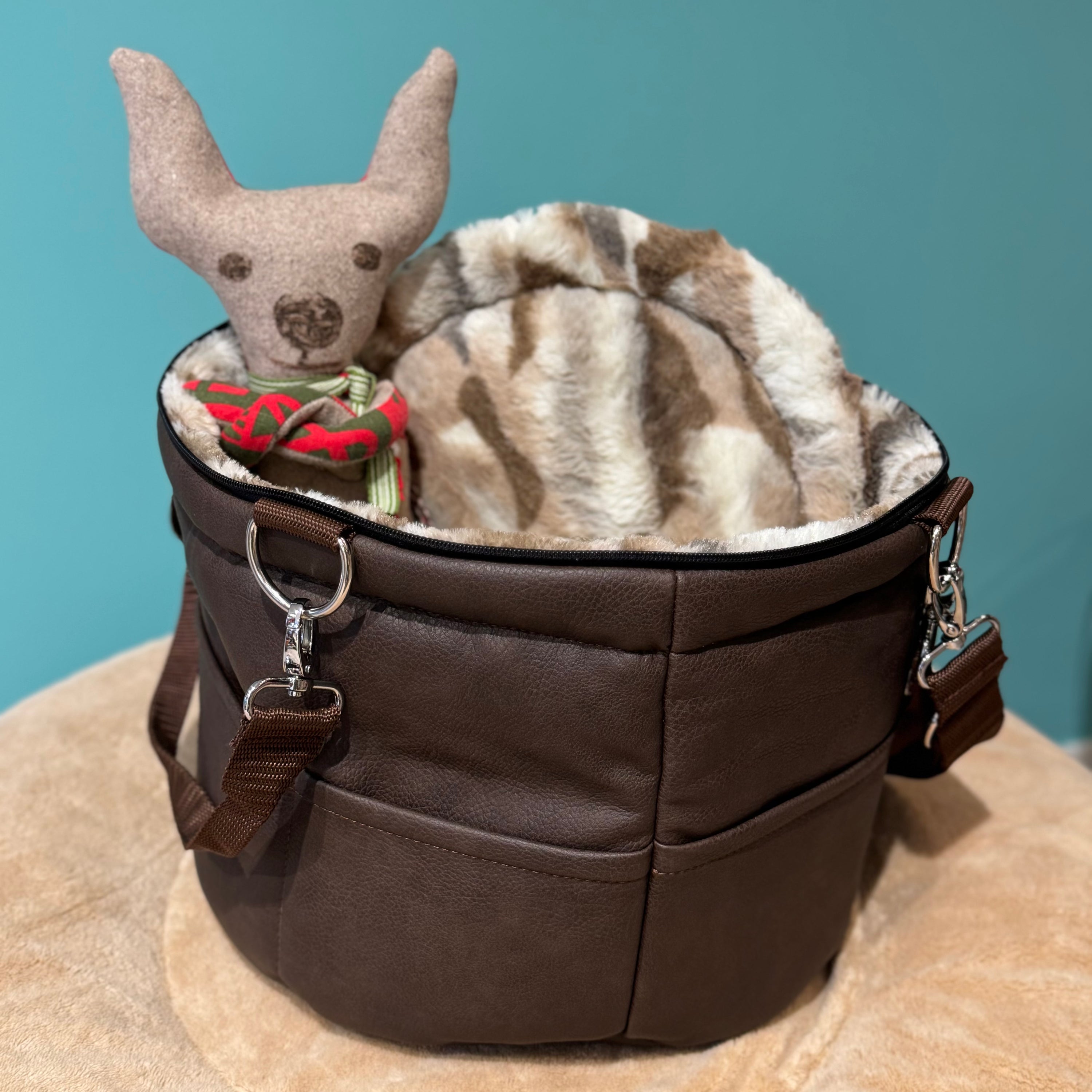 Isarhund Herzflug Tasche in Braun mit flauschigem Kunstfell-Rand und weichem Innenfutter, inklusive herausnehmbarer Netzeinsätze und verstellbarem Schultergurt, komfortable Hundetragetasche für kleine Hunde. Ein Spielzeughund sitzt in der Tasche.