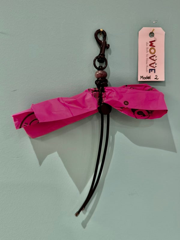 Handgefertigter Isarhund Kotbeutelhalter aus Leder mit schwarzem Karabinerhaken, befestigt an einer Wand, mit pinken Kotbeuteln und Markenanhänger, Made in Bavaria