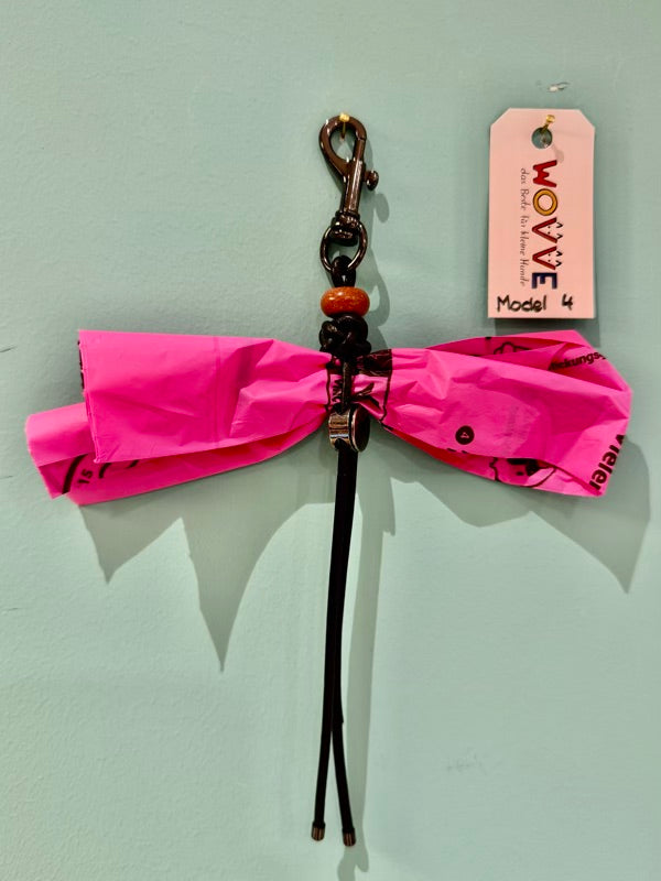 Handgefertigter Isarhund Kotbeutelhalter aus Leder mit schwarzem Karabinerhaken, befestigt an einer Wand, mit pinken Kotbeuteln und Markenanhänger, Made in Bavaria