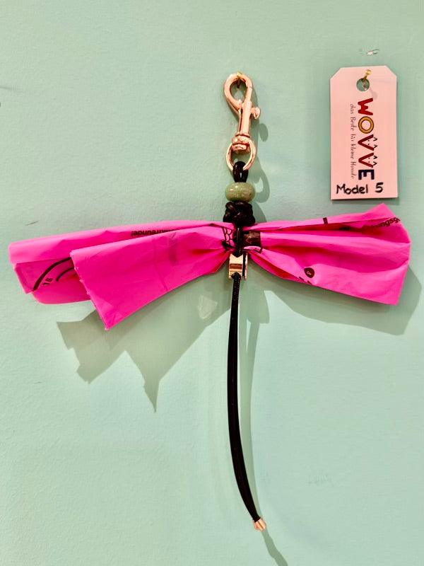 Handgefertigter Isarhund Kotbeutelhalter aus Leder mit goldfarbenem Karabinerhaken, befestigt an einer Wand, mit pinken Kotbeuteln und Markenanhänger, Made in Bavaria