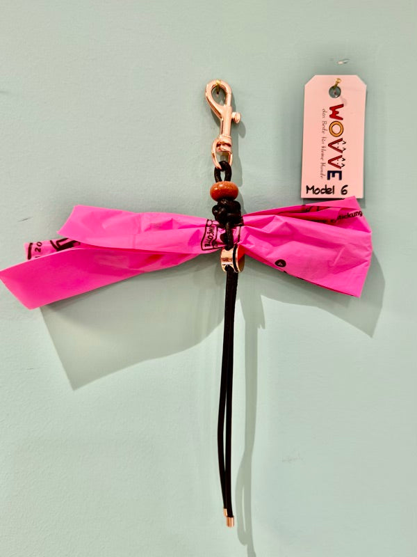 Handgefertigter Isarhund Kotbeutelhalter aus Leder mit silbernem Karabinerhaken, befestigt an einer Wand, mit pinken Kotbeuteln und Markenanhänger, Made in Bavaria