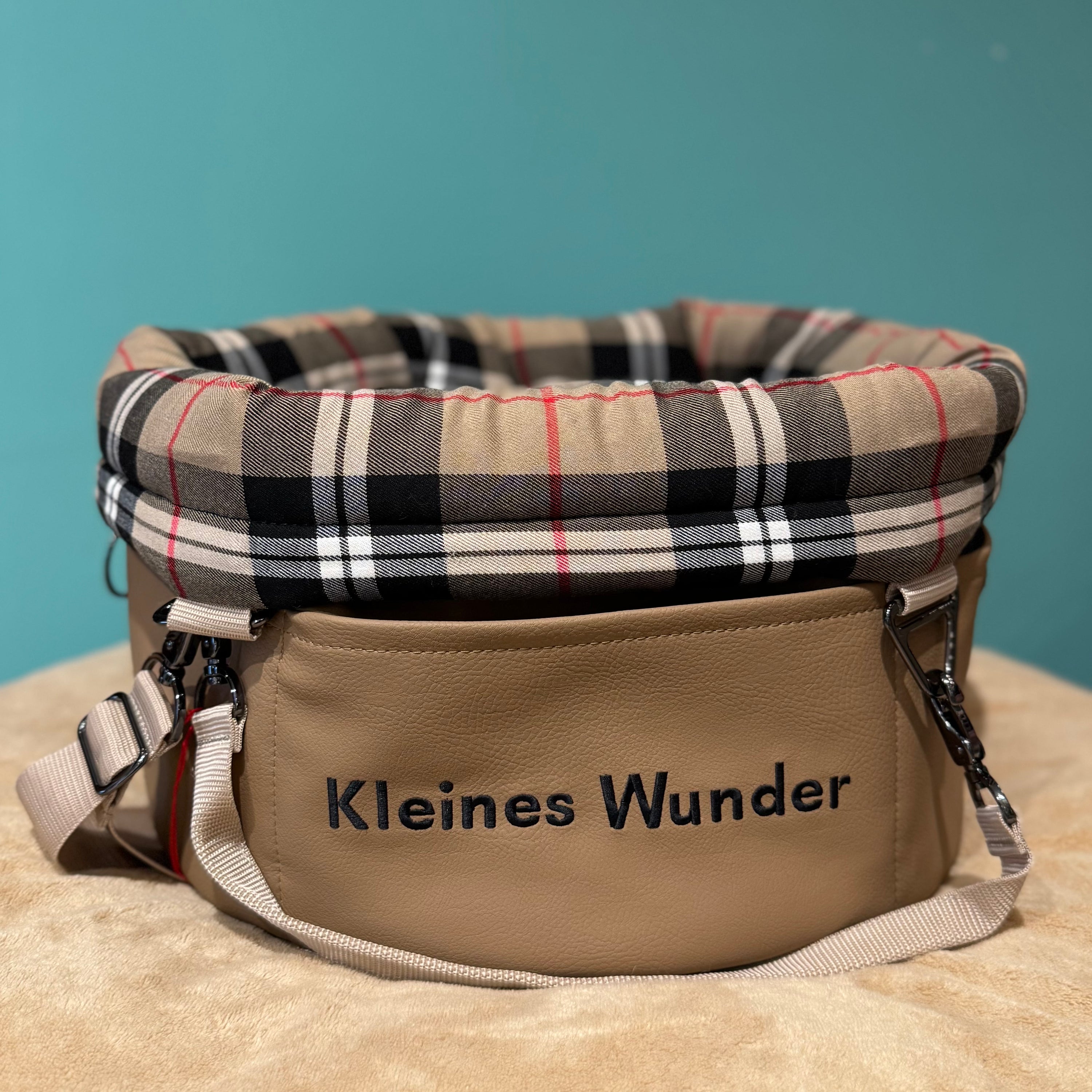 Isarhund Herzstück Tasche in Beige mit kariertem, weich gepolstertem Rand, bestickt mit Schriftzug „Kleines Wunder“, verstellbarem Schultergurt und Karabinern, komfortable Hundetragetasche für kleine Hunde
