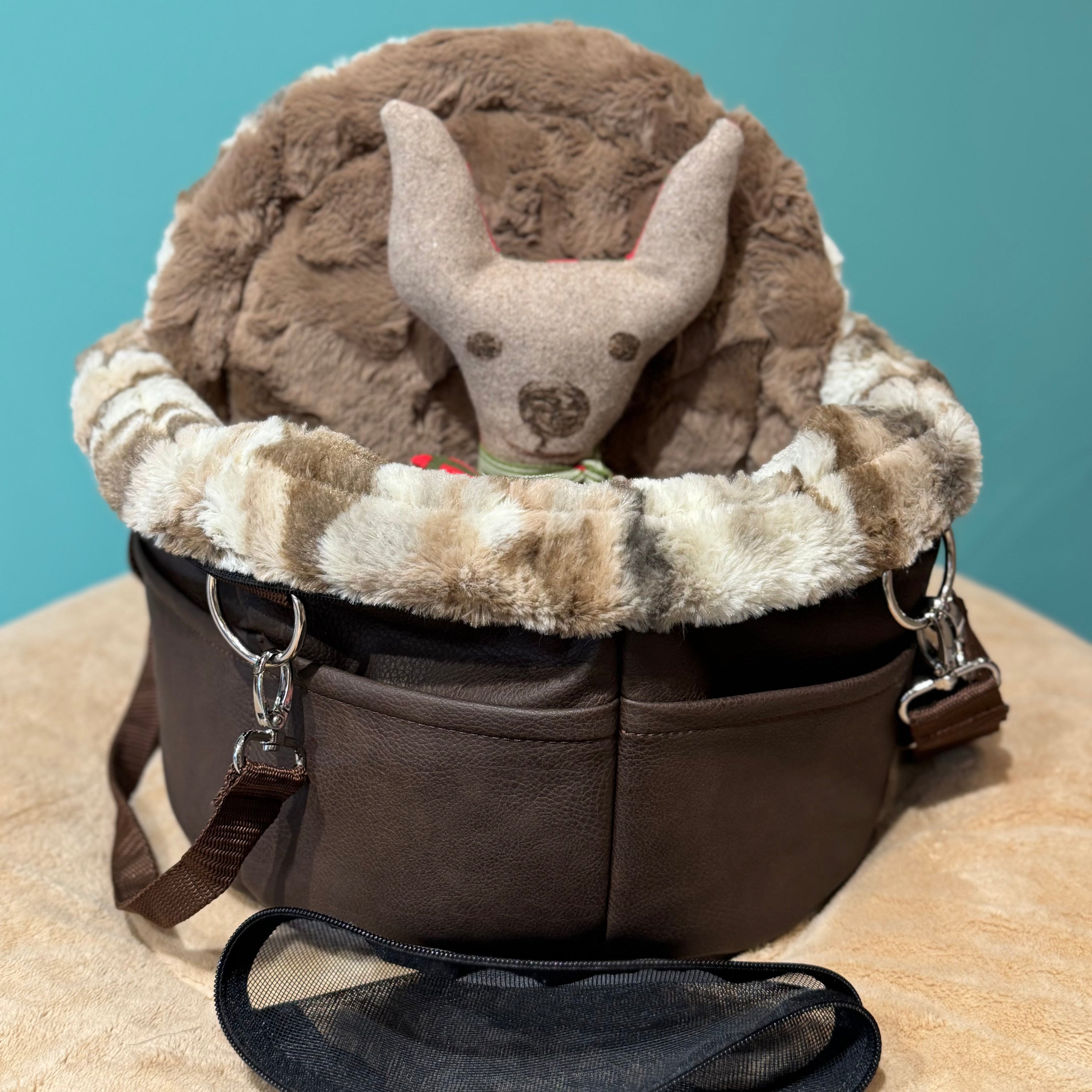 Isarhund Herzflug Tasche in Braun mit flauschigem Kunstfell-Rand und weichem Innenfutter, inklusive herausnehmbarer Netzeinsätze und verstellbarem Schultergurt, komfortable Hundetragetasche für kleine Hunde. Ein Spielzeughund sitzt in der Tasche.