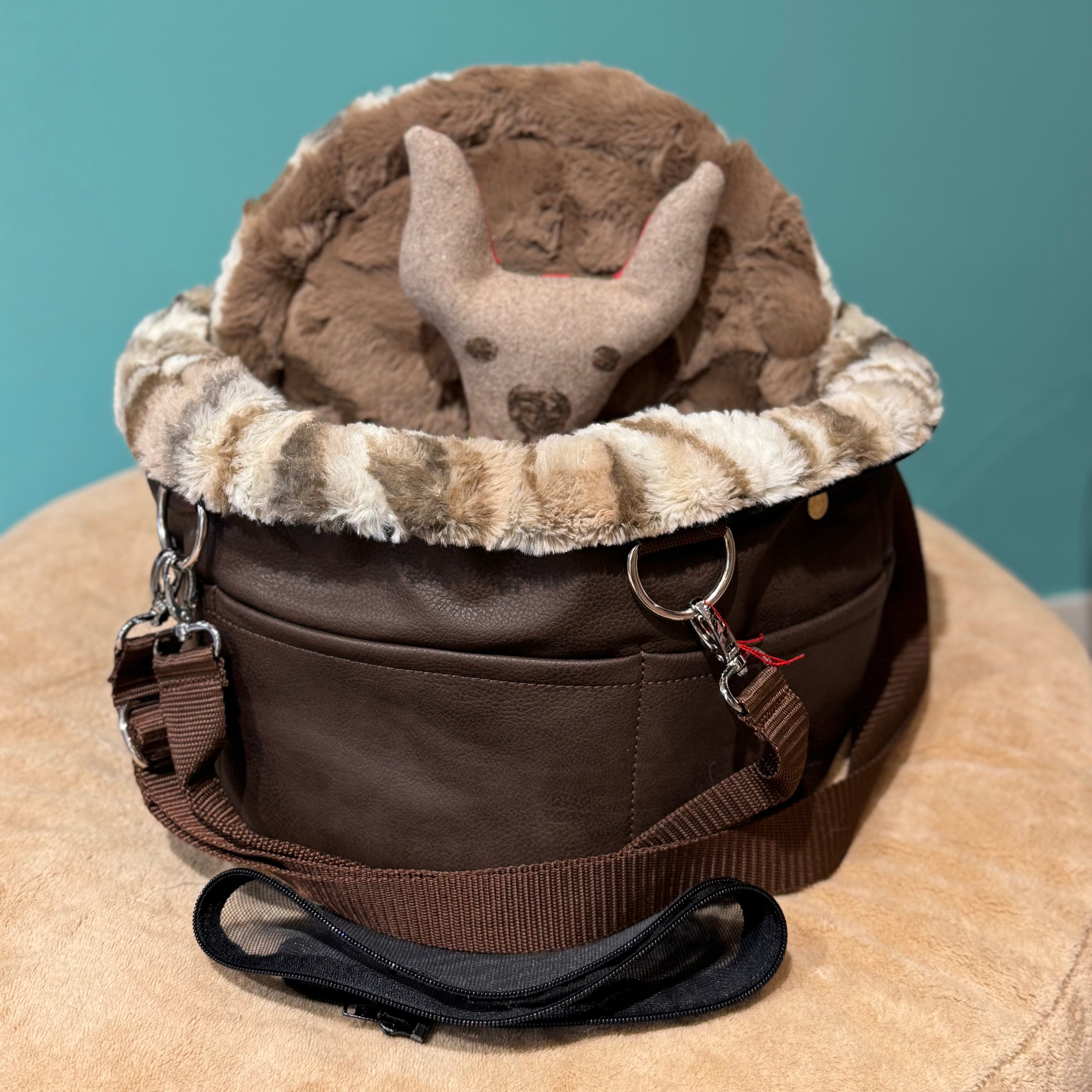 Isarhund Herzflug Tasche in Braun mit flauschigem Kunstfell-Rand und weichem Innenfutter, inklusive herausnehmbarer Netzeinsätze und verstellbarem Schultergurt, komfortable Hundetragetasche für kleine Hunde. Ein Spielzeughund sitzt in der Tasche.
