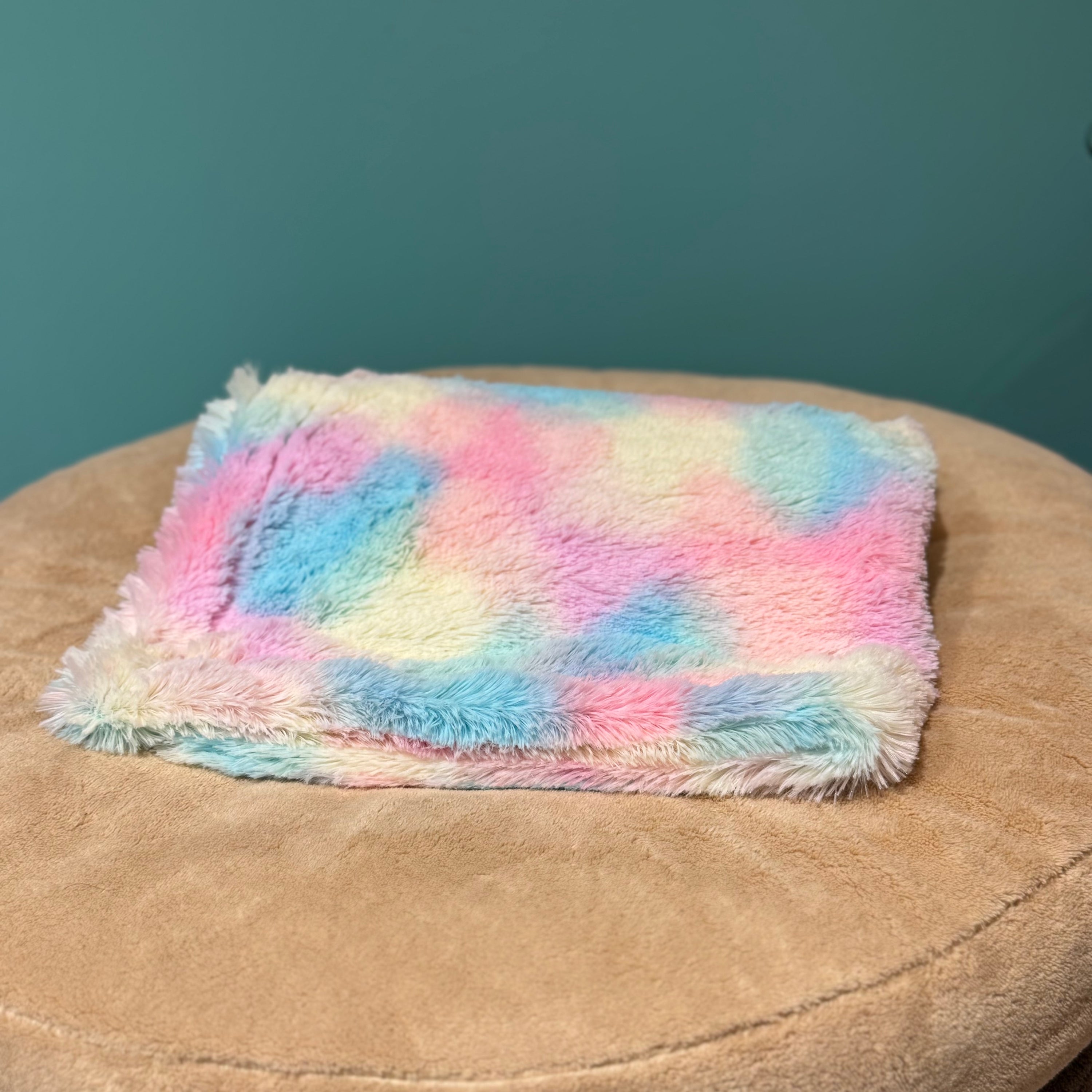 Isarhund Kunstfell-Decke in Pastellfarben mit weicher, flauschiger Oberfläche, dekorativ gefaltet auf beigem Hundebett, ideal als kuschelige Hundedecke für Zuhause oder unterwegs