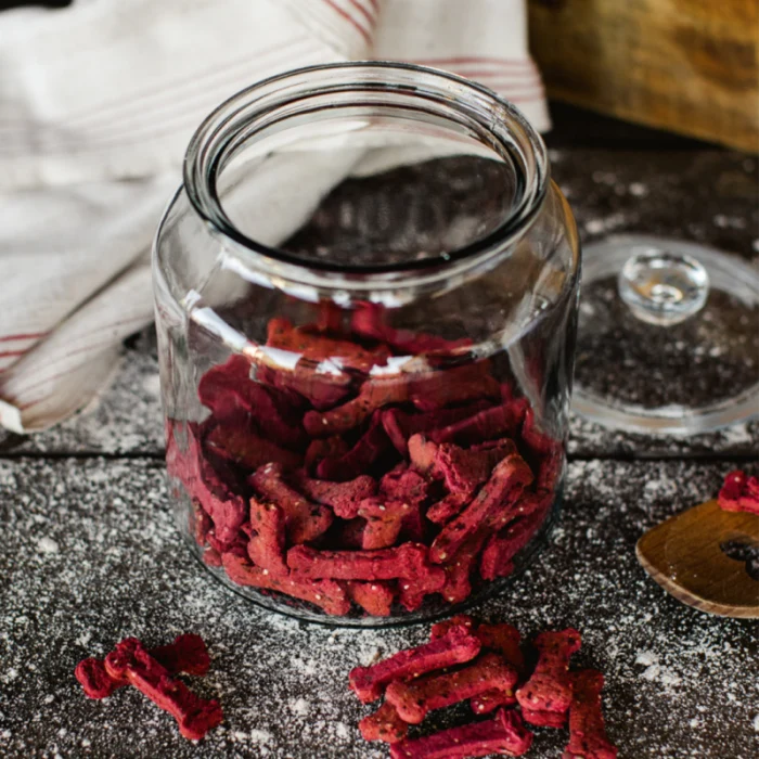 Rote Hundekekse in Knochenform in einem geöffneten Glas