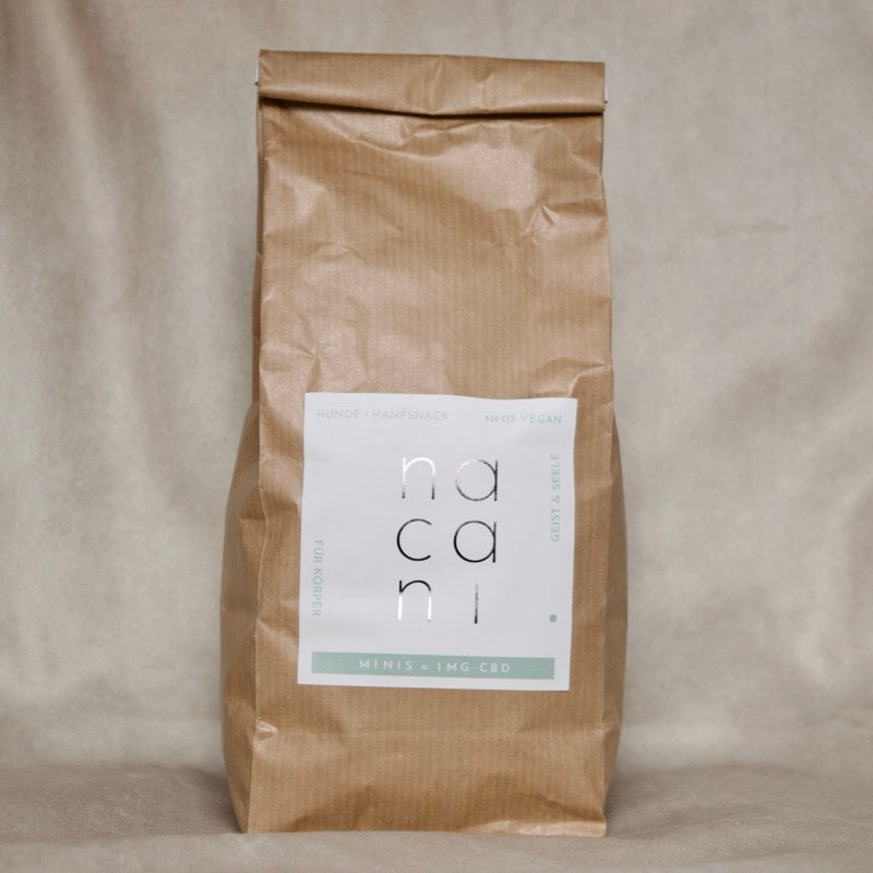 Braune Vorratspackung mit Label „nacani Minis – 1mg CBD“, vegane Hunde-Hanfsnacks in nachhaltiger Papierverpackung, Produktaufnahme vor neutralem Hintergrund.
