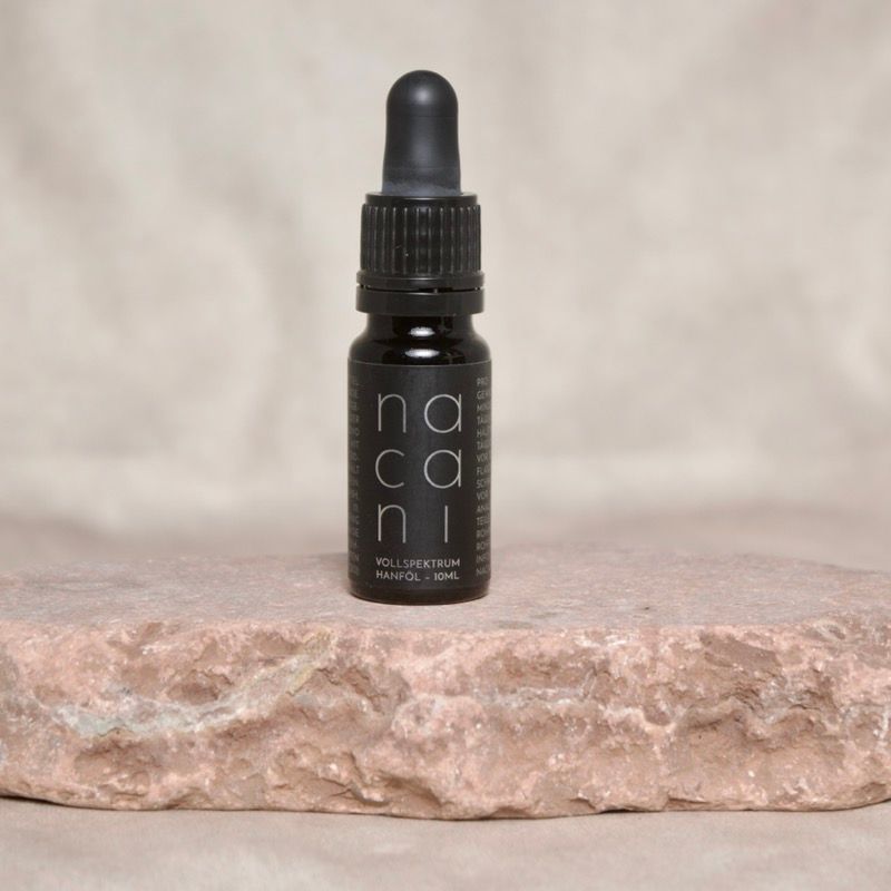 Nacani CBD Öl 2,8 Prozent in dunkler Glasflasche mit Pipette, auf natürlichem Stein vor neutralem Hintergrund platziert.