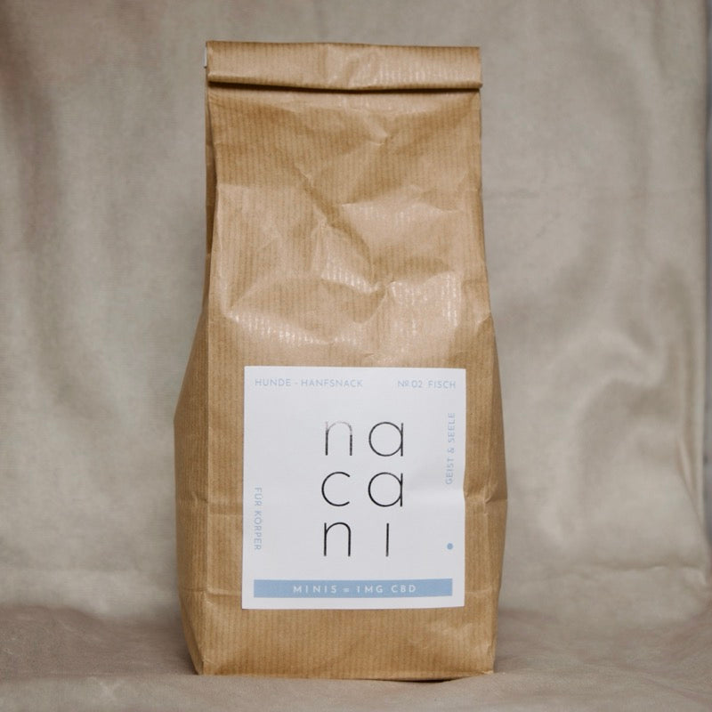 Braune Vorratspackung „nacani Minis – 1mg CBD“, Hunde-Hanfsnacks mit Fisch, nachhaltige Papierverpackung mit weiß-blauem Etikett vor neutralem Hintergrund.