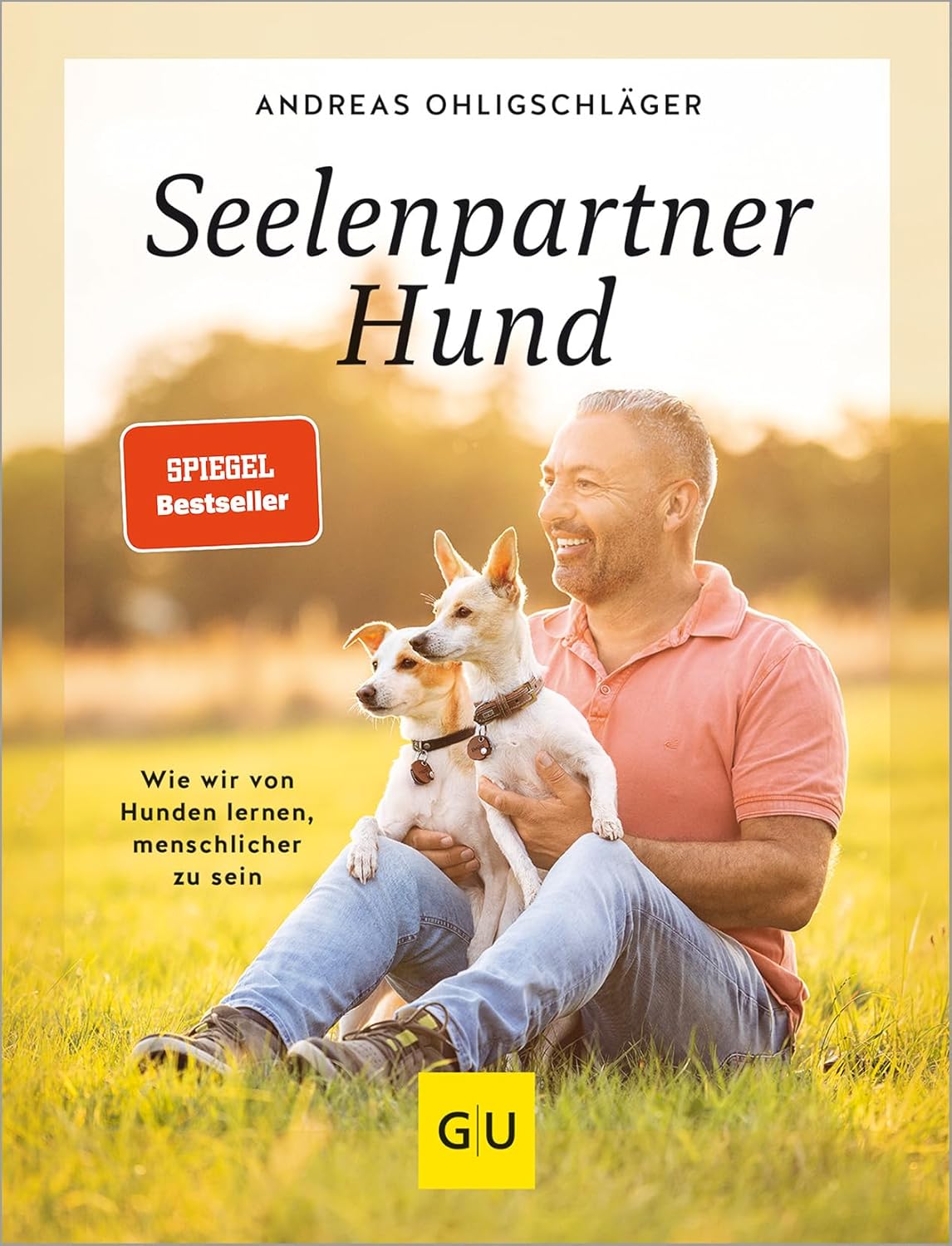 Buchcover Ohligschläger Seelenpartner Hund. Mann sitz mit Hund auf einer Wiese mit 2 Hunden auf dem Schoß
