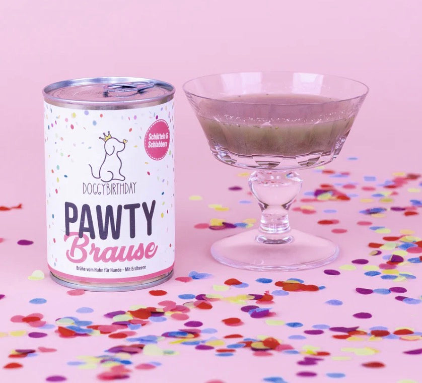 Eine Dose mit Pawty Brause und ein Glas mit roter Flüssigkeit auf einem rosa Hintergrund mit Konfetti