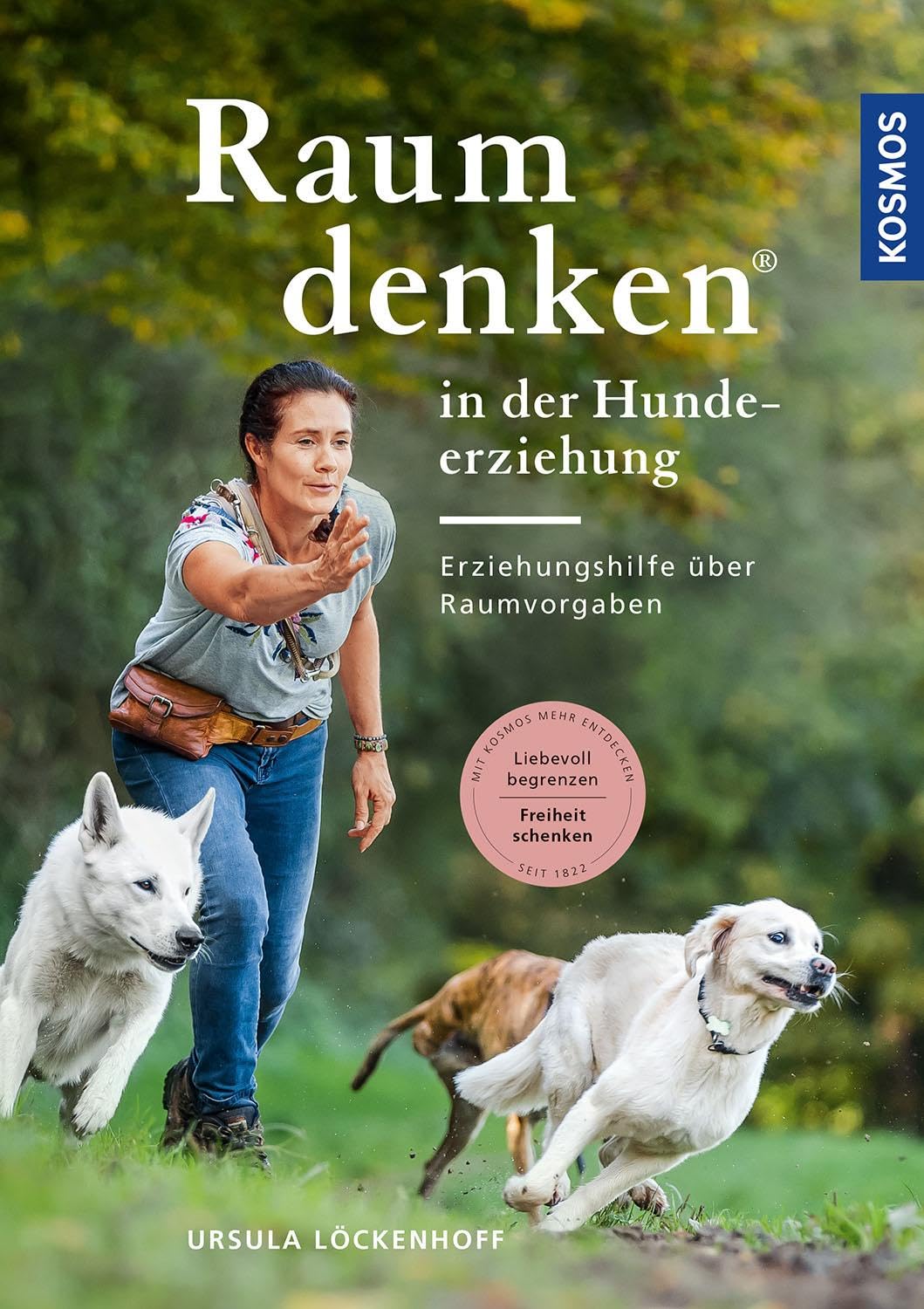 Buch ‚Raumdenken in der Hundeerziehung‘ von Ursula Löckenhoff, Cover mit Trainerin und zwei Hunden in Bewegung auf einer Wiese.