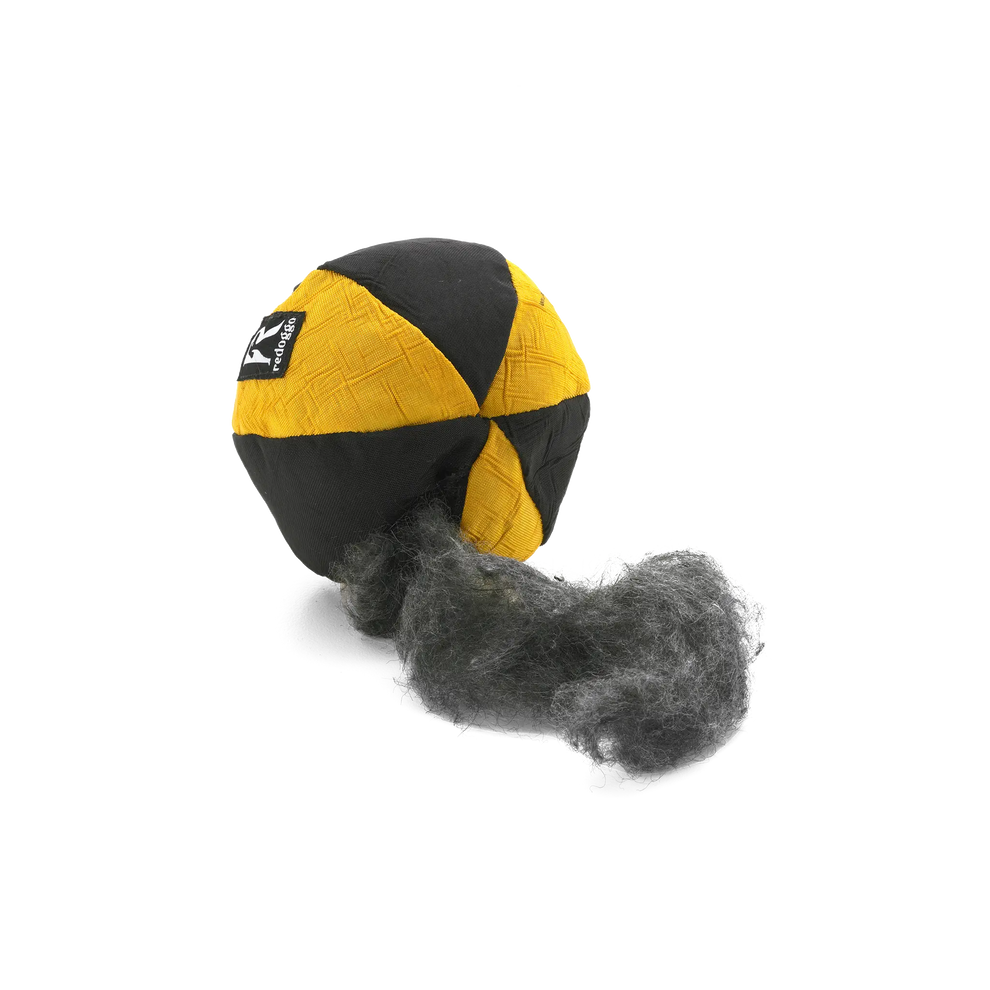 Gelb-schwarzer Redoggo Hundeball mit geöffneter Naht und sichtbar austretender Füllung aus kurzfaserigem Upcycling-Material.