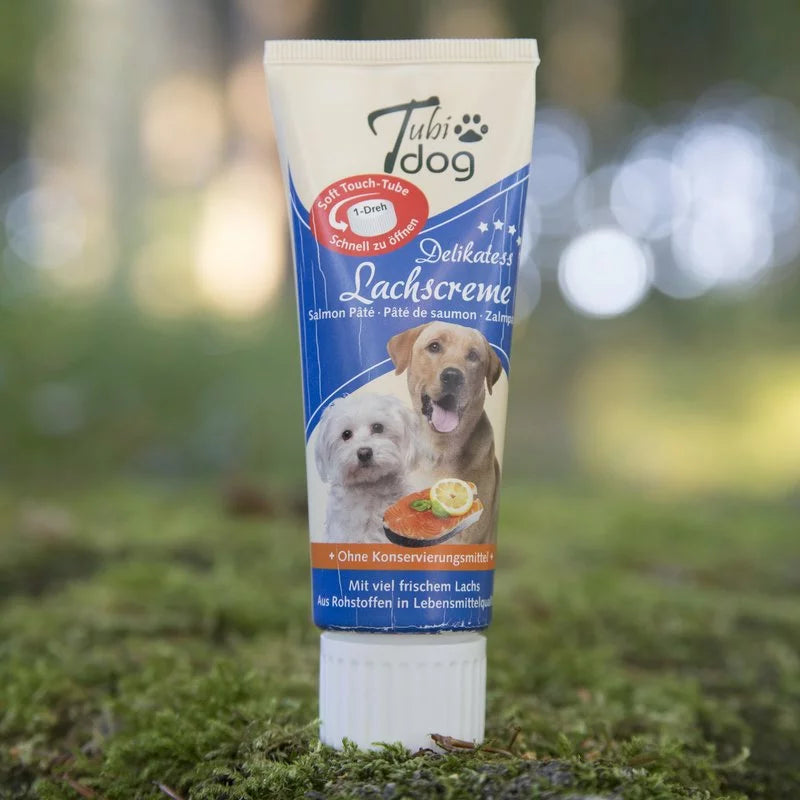Tube mit Lachscreme Hundeleckerli auf Rasenfläche 