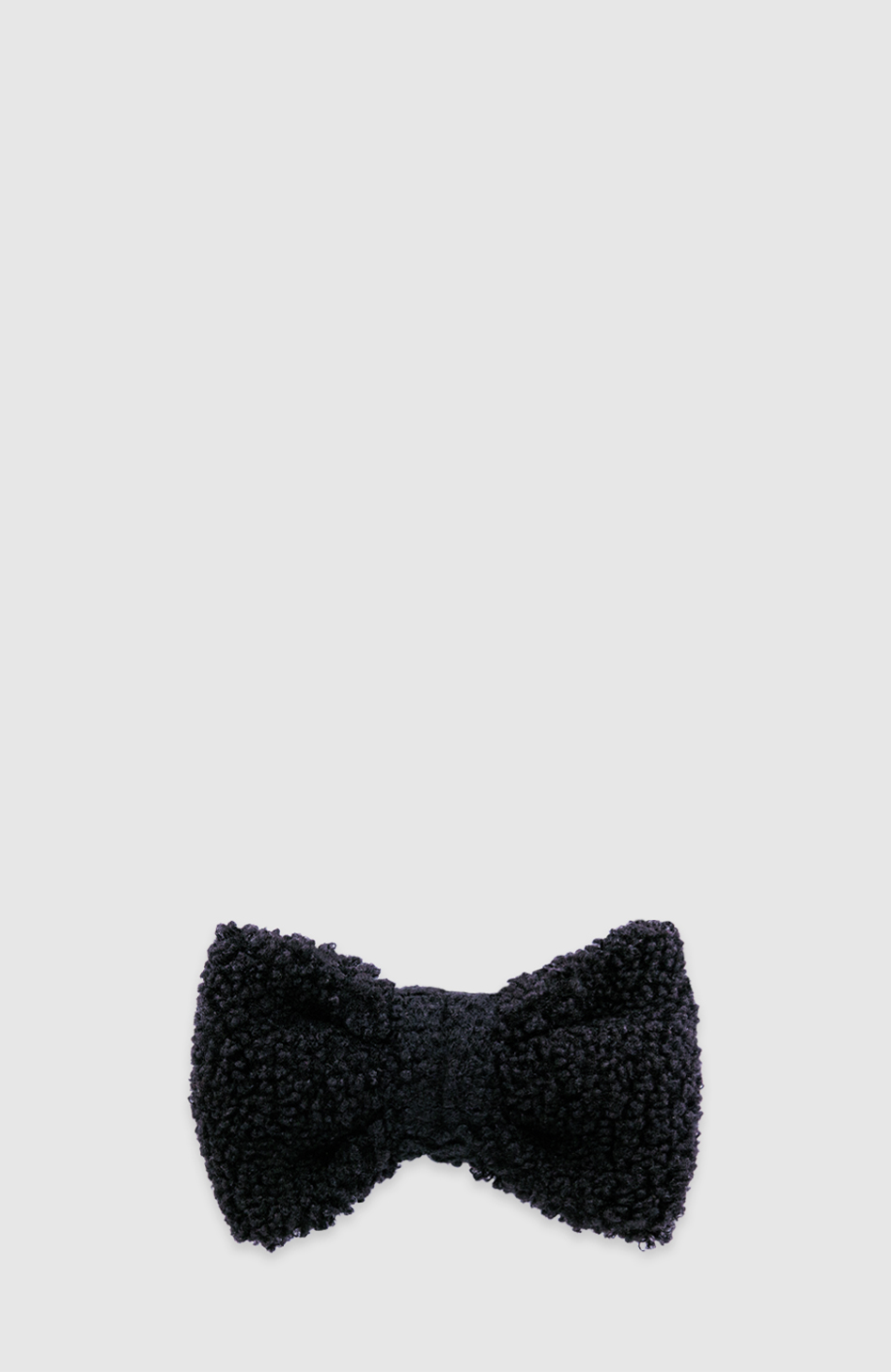 Schwarze Teddy-Fliege für Hunde von Nacani, dekoratives Accessoire zur Aufnahme des Relax Buddy Öls, weich und flauschig, fotografiert vor hellem Hintergrund.